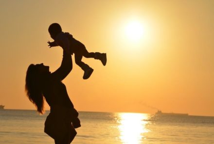 mom tossing baby in air on the beach during sunset