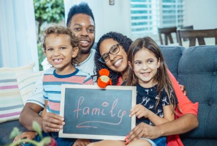 adoption parents holding family sign with kids