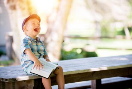 boy laughing while holding a book